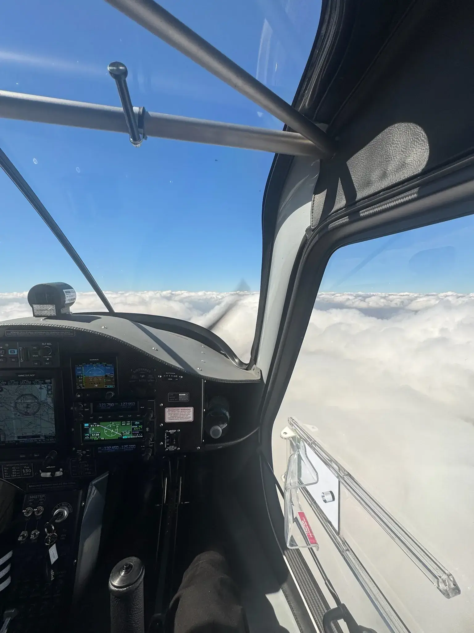 Airplane cockpit instrument panel during flight with clouds below seen from the cockpit's windows