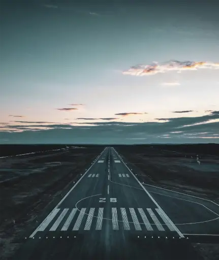 Airport runway with clouds and sunset in the horizon