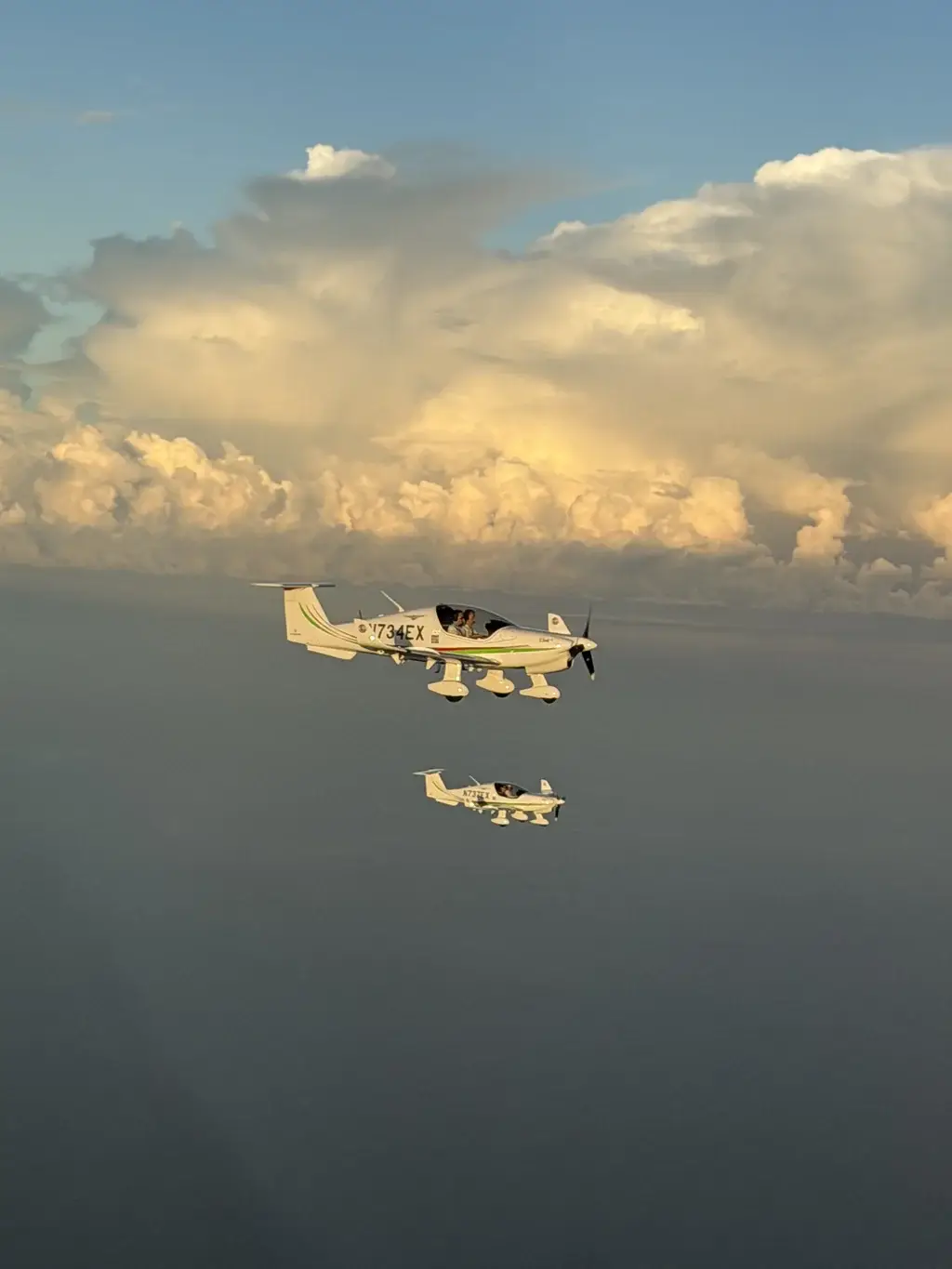 Two Cirrus Aviation Elixir aircraft flying in formation in front of towering clouds
