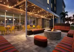 Home2 hotel's outside sitting area with tables, chairs and a fireplace