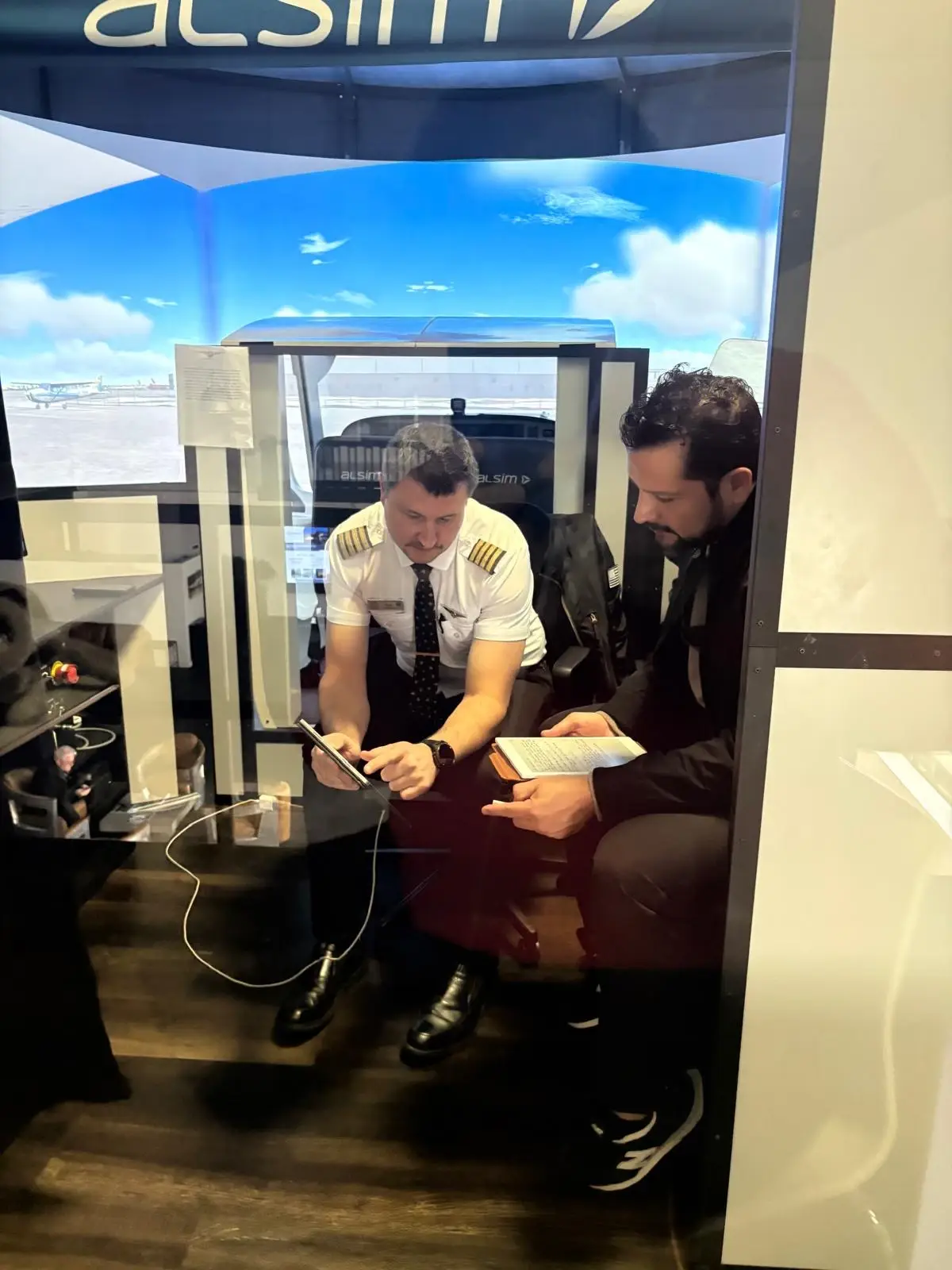 Instructor reviewing notes with a student inside the Alsim simulator cockpit