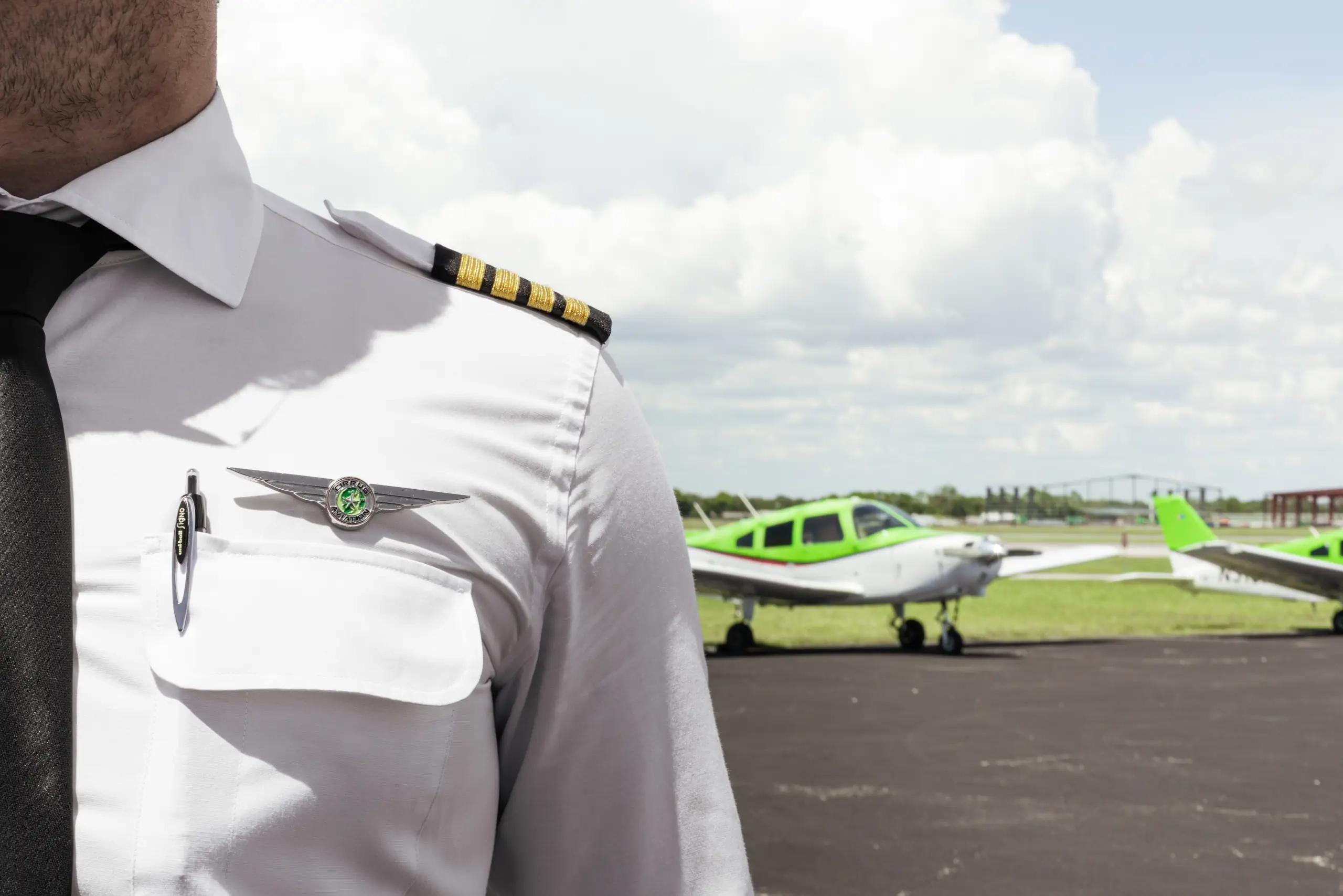Pilot in uniform torso close-up with Cirrus Aviation logo and aircraft in the background