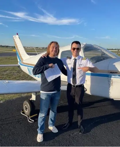 Student and CFI commemorating in front an airplane with certification in hand