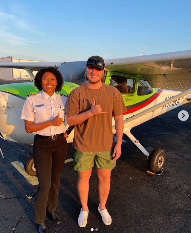 Student and instructor celebrating a first solo flight in front of a training aircraft