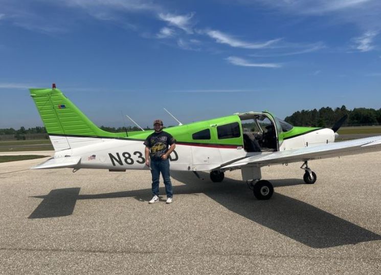 Student in front of a Piper Warrior aircraft