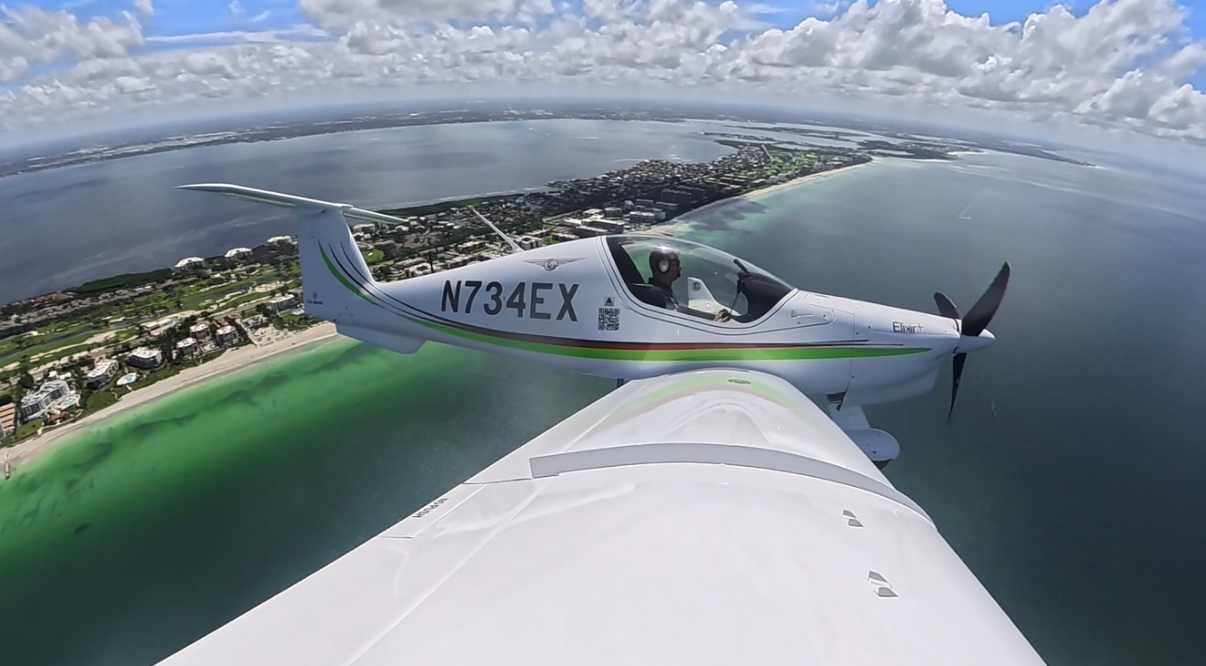 Elixir Aircraft N734EX flying over sea, side wing view