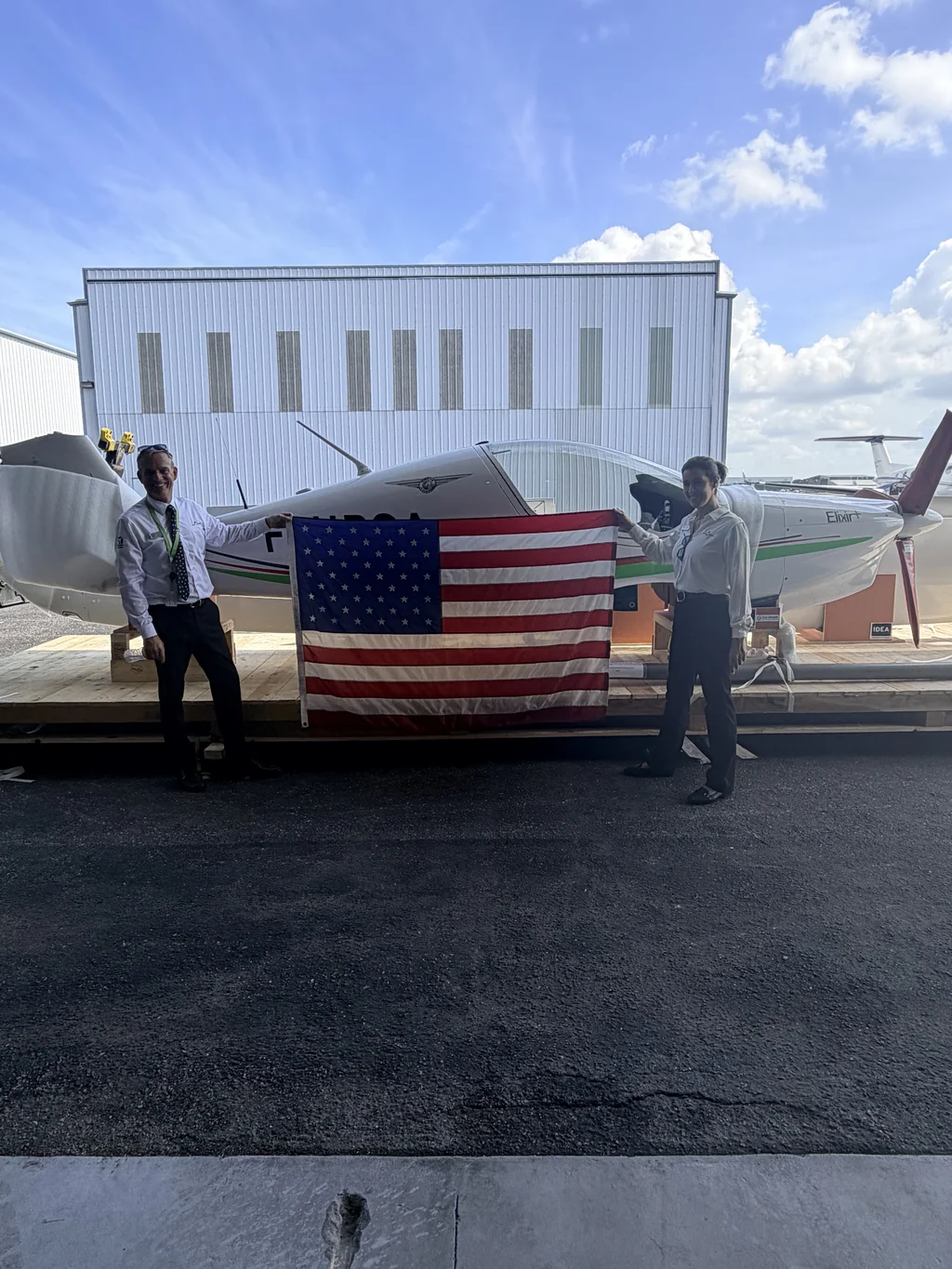 David and Nayda Cattin holding a United States flag beside the newly arrived Elixir aircraft in Sarasota