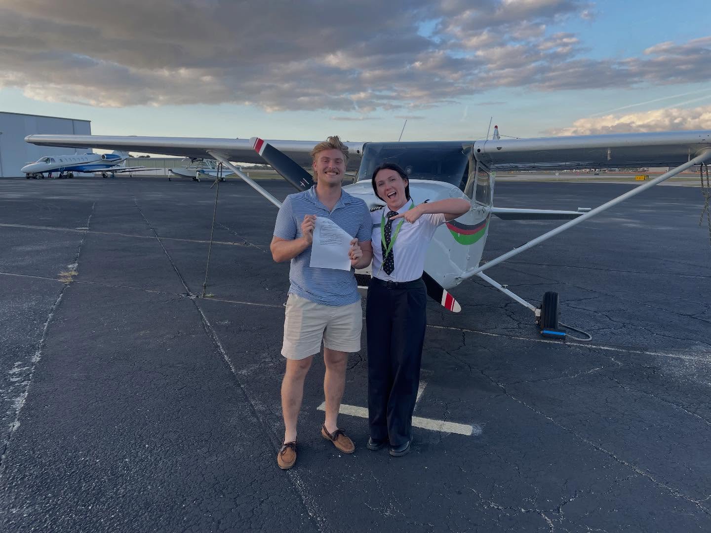 Private Pilot student and instructor celebrating with a certificate in front of a training aircraft